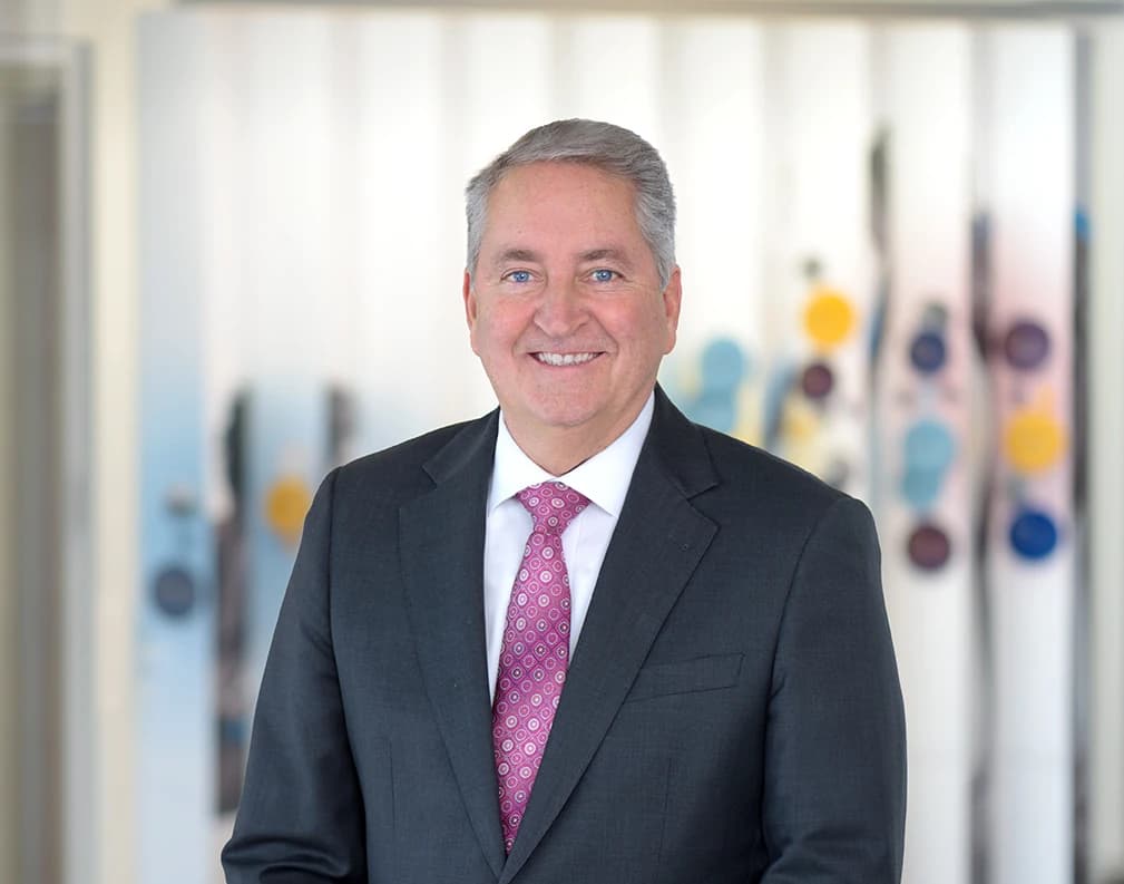 Tom Lampe in a charcoal suit and patterned tie, photographed in 2026.